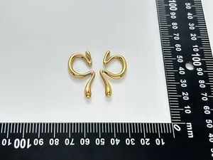 Détail de boucles d'oreilles minimalistes dorées avec règle de mesure