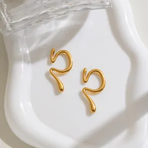 Détail de manchette d'oreille en acier doré au design liquide incurvé sur plateau blanc