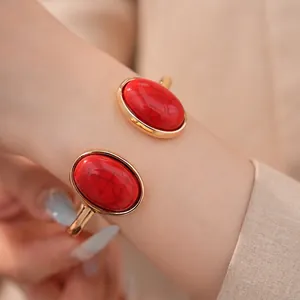 Eleganter goldfarbener Armreif mit zwei großen ovalen roten Schmucksteinen für Damen