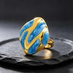 Primer plano de un anillo de acero de titanio dorado con patrones abstractos de esmalte azul