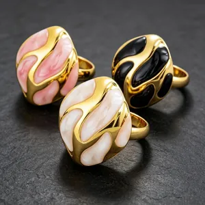 Primer plano de tres anillos de esmalte abstracto y acero de titanio chapado en oro de colores.