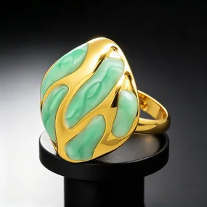 Vista detallada del anillo chapado en oro con motivos fluidos abstractos de esmalte verde.