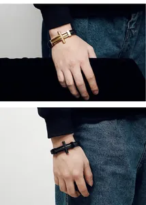 Detailaufnahme eines Herrenarmbands im Punk-Stil mit geflochtenem Leder und Kreuzmotiv