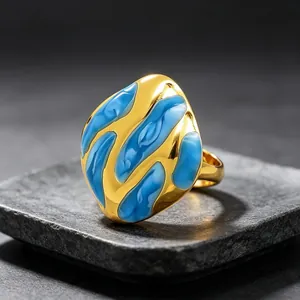 Primer plano de anillo bañado en oro con diseño de esmalte azul fluido.