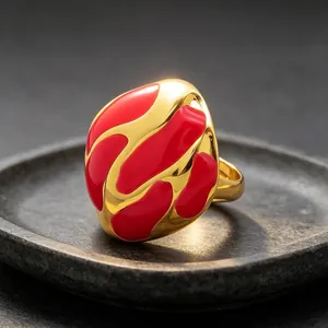 Primer plano de anillo abstracto de esmalte rojo y oro con patrón fluido en piedra