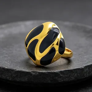 Primer plano de un anillo abstracto de acero inoxidable chapado en oro con esmalte negro