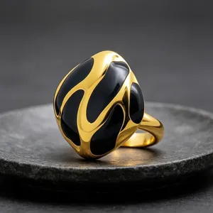 Vista detallada de un anillo dorado abstracto con patrones ondulados de esmalte negro