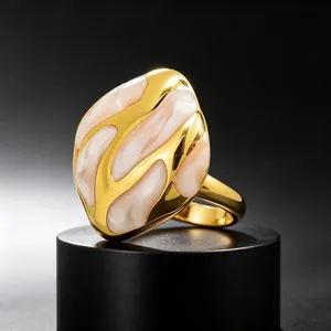 Primer plano de un anillo dorado de diseño abstracto con esmalte rosa fluido
