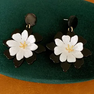 Macro view of retro French vintage black and white acrylic flower stud earrings.