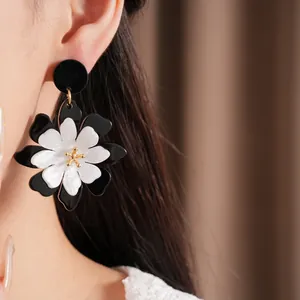 Close-up detail of a vintage black and white acrylic flower earring worn on a model's ear.