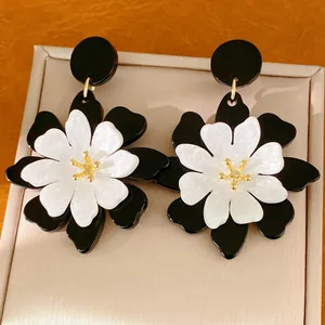 Close-up view of vintage black and white acrylic floral earrings with golden details