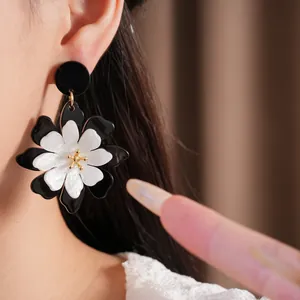 Macro detail view showing retro black and white layered acrylic flower earrings worn on ear