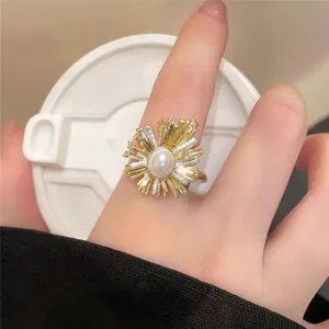 Nahaufnahme eines eleganten, 18k vergoldeten Rings mit Sonnenstrahlen-Design und Perle