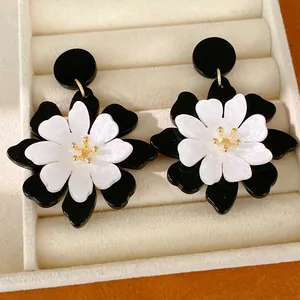 Close-up detail of French retro style black and white layered acrylic flower stud earrings.