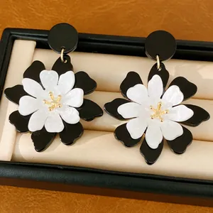 Close-up detail of stylish black and white acrylic flower earrings displayed in jewelry box