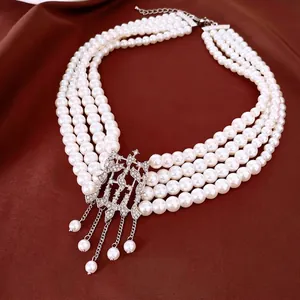 Collier de perles blanches multicouches avec pendentif géométrique en strass sur fond brun