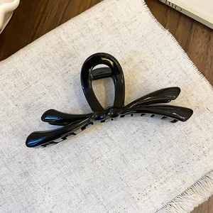 Primer plano de una pinza para el pelo con lazo negro brillante sobre fondo de lino beige