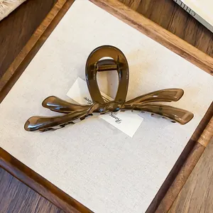 Vista detallada de una pinza para el cabello con forma de lazo marrón ámbar sobre fondo blanco