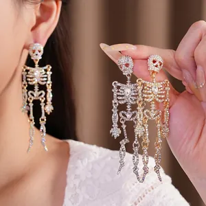 Übergroße, mit Strass besetzte Totenkopf-Ohrringe mit Quasten in Gold und Silber.