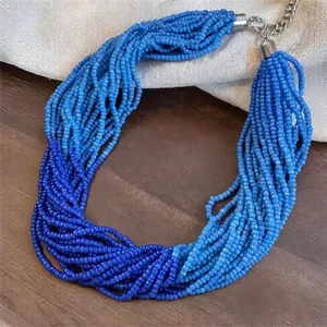 Makroansicht der mehrsträngigen Glasperlenkette in Blauverlauf auf Holzoberfläche