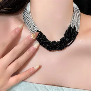 Nahaufnahme einer mehrlagigen schwarz-weißen Glasperlenkette am Hals des Models.
