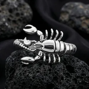 Detailed close-up of a masculine silver titanium steel scorpion ring on black volcanic rock.
