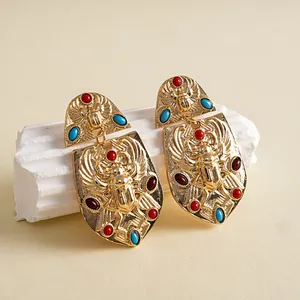 Pendientes de escarabajo dorados vintage con piedras acrílicas sobre soporte de piedra.