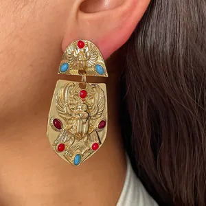 Vista detallada de pendientes vintage de escarabajo dorado con piedras de colores