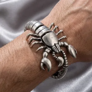 Close-up view of a detailed vintage silver scorpion cuff bracelet on a man's wrist.
