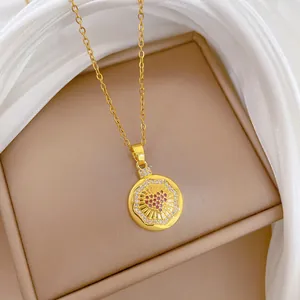 Nahaufnahme eines goldenen runden Anhängers mit rotem Herz-Zirkon und funkelnden Diamanten