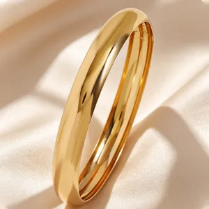 Primer plano detallado de un brazalete de oro pulido espejo sobre elegante tela de satén