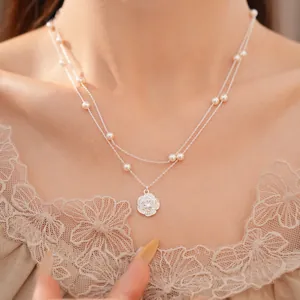 Vista detallada del collar de dos capas con elegantes perlas y un colgante de flor de circón