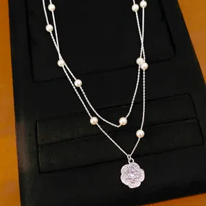 Detalle de collar de dos capas con perlas y colgante de flor de circón