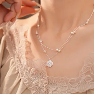 Elegante collar de doble capa con perlas delicadas y un colgante de flor de circón brillante.