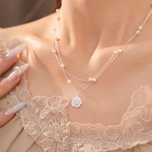 Detalle de un elegante collar de doble capa plateado con perlas y colgante de flor