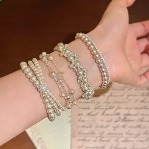 Detailopname van elegante parelarmbanden in Franse stijl met zirkonia-accenten om de pols