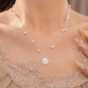 Primer plano detallado de un collar de doble capa con colgante de flor de circón y perlas