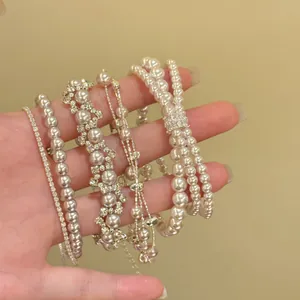 Detailweergave van diverse Franse stijl parel- en zirkonia-armbanden getoond op een hand.