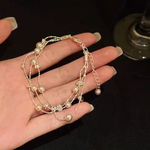 Detailweergave van een elegante meerlaagse parelarmband met metalen accenten.