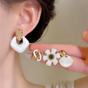 Élégant ensemble de boucles d'oreilles blanches rétro à fleurs et géométriques sur l'oreille