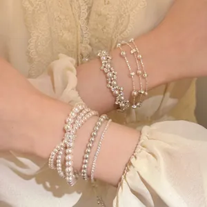 Gedetailleerd overzicht van elegante gelaagde parel- en zirkonia-armbanden in zachte Franse stijl