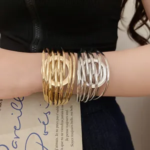 Gros plan de bracelets enroulés multicouches or et argent au poignet, design épuré.