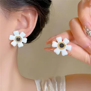 Détail de boucles d'oreilles fleurs blanches élégantes avec centres dorés et noirs sur l'oreille