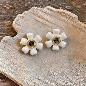 Vue détaillée de boucles d'oreilles rétro en forme de fleur blanche avec centre doré