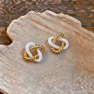 Vue détaillée de boucles d'oreilles géométriques vintage dorées et blanches entrelacées
