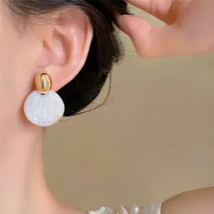 Gros plan de boucles d'oreilles vintage dorées avec pendentifs circulaires blanc nacré
