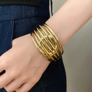Détail d'un bracelet jonc doré multicouche à cercles entrelacés porté au poignet d'une femme