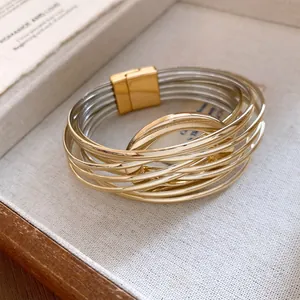 Détail d'un bracelet multicouche chic en fils d'or et d'argent avec fermoir magnétique.