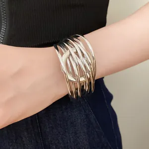 Détail d'un bracelet manchette argenté à plusieurs rangs enroulé sur un poignet