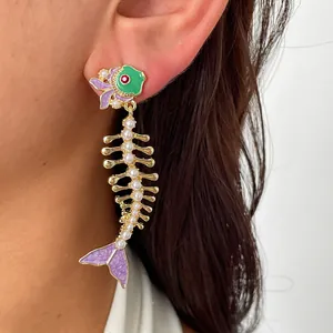 Gros plan sur une boucle d'oreille créative en arête de poisson avec émail violet et perles